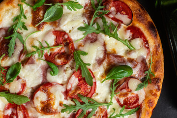 Pizza with ham,tomatoes and mozzarella on a dark background