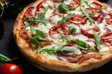 Pizza with ham,tomatoes and mozzarella on a dark background