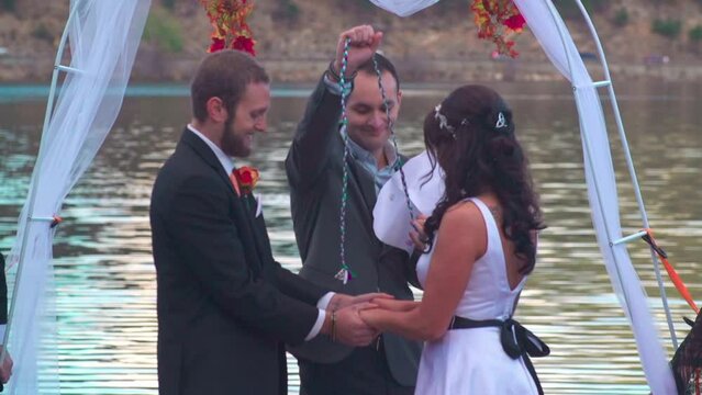 Caucasian wedding officiant ties the groom and bride to read the blessing script during the wedding