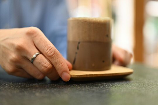 Close up and cropped image of man's hands holding Hojicha iced latte.