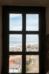 Scenic view of a beach through a window, with a few boats parked on the beach