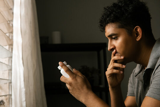 Adult Man Holding And Looking At A Bottle Of Pills. Concept Mental Health And Antidepressants.