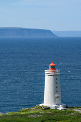 Fototapeta na wymiar Skardsviti Lighthouse along the edge of a cliff on a sunny day near Hvammstangi, Iceland