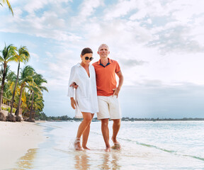 Couple in love hugging while walking on a sandy exotic beach. They have an evening walk by Trou-aux-Biches seashore on Mauritius island. People relationship and tropic honeymoon vacations concept