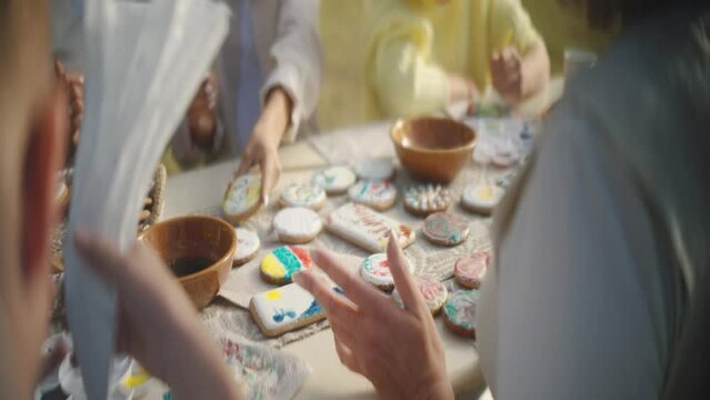Close-up view of people decorating cookies with paint and icing