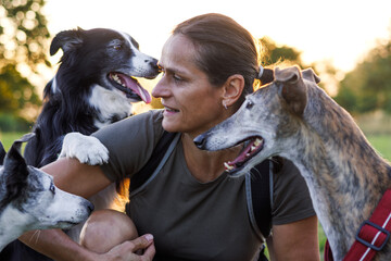 Happy woman is playing with adopted dogs from animal shelter