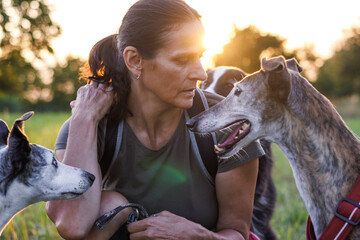 Pet owner with her dogs resting during dog walking outdoors. Friendship between woman and animal