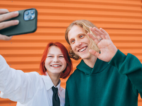 Portraits of two smiling caucasian teen friends boy and girl posing for selfie using a smartphone. Careless young teenhood . time and modern technology concept image.