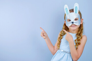 A child in a masquerade carnival mask of a hare or a rabbit, made by hand from shiny glitter...