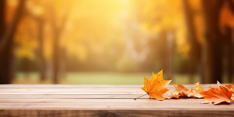 Naklejka na ściany i meble Wooden planks and orange dry leaf against the background blurred tree foliage of trees in beautiful autumn park. Autumn universal background for presentation