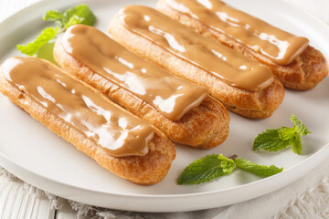 French sweet eclairs with cream filling and topped with soft delicate caramel close-up in a plate on the table. Horizontal