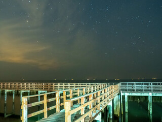 Sea view near mangrove forest with man made wooden barrier for wave protection, under starry nigh cloudy sky in Bangkok, Thailand