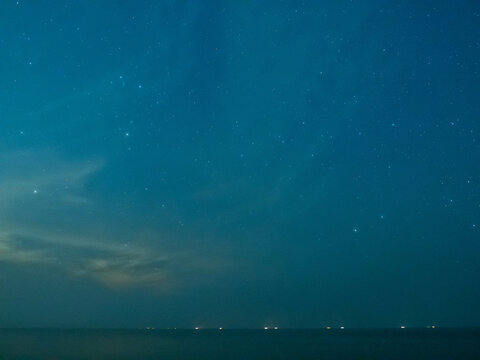 Sea view near mangrove forest with man made wooden barrier for wave protection, under starry nigh cloudy sky in Bangkok, Thailand
