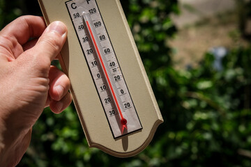 Ice cubes melting in direct sun next to a home thermometer showing over 40 degrees Celsius during a...