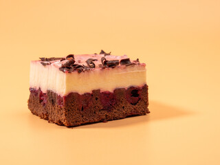 Cherry cake with chocolate on an orange background. Cream cake with cherries and chocolate.