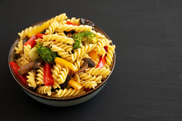 Homemade Garlic Veggie Rotini Pasta in a Bowl on a black background, side view. Copy space.