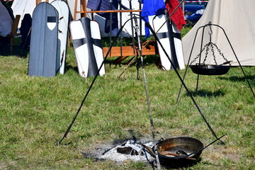 A close up on a medieval camp full of targes, shields, cloth tents, weaponry, and utensils for...