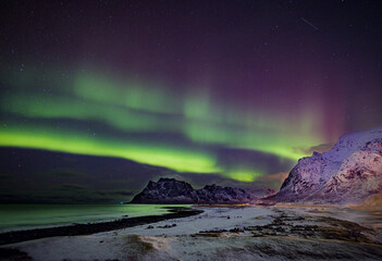 Bright green and magenta colors of the aurora borealis fill the sky in Norway