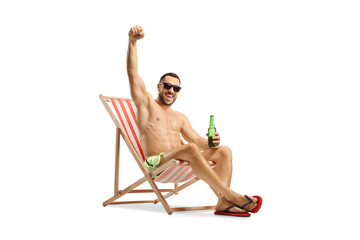 Man at a beach chair holding a bottle of beer and gesturing happiness