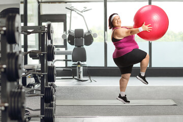 Fototapeta premium Cheerful overweight woman exercising with a fitness ball