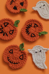 Funny crochet Halloween pumpkins and ghost close up on an orange background.