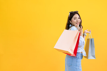 portrait of young Asian pretty woman holding shopping bags in hands enjoy buying gifts in store...