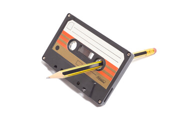 Audio cassette tape with pencil isolated on white background, vintage 80's music concept.
