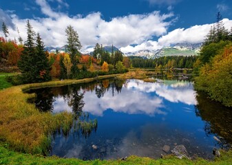 Naklejka premium Beautiful mountain lake with a reflection of autum park on water and high peaks in the Background. The new Strbske pleso lake in High Tatras mountains in Slovakia.