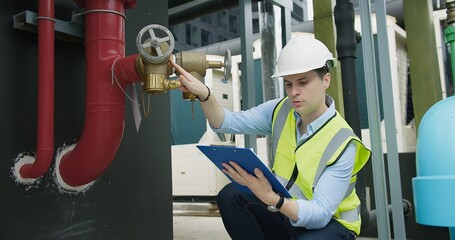 Portrait Professional Inspector Engineer foreman in hardhat working checking the valve pipelines and recheck system data spec on rooftop of construction site