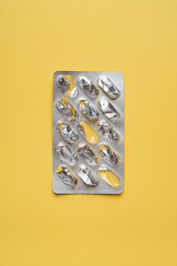 Empty pills blister pack on yellow background. Used tablet packaging.