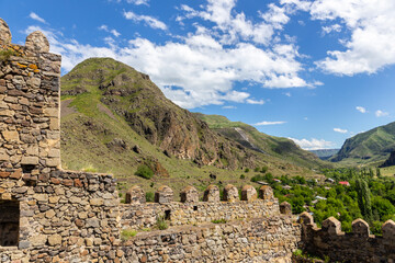 Khertvisi Fortress stone defence crenellated wall with battlements and Mtkvari (Kura) and Paravani river valley view and green Lesser Caucasus mountains in the background, Meskheti region, Georgia.