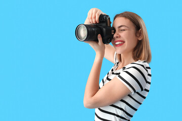 Female photographer with professional camera on blue background