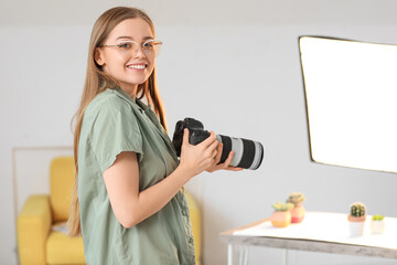 Young female photographer with professional camera in studio - obrazy, fototapety, plakaty
