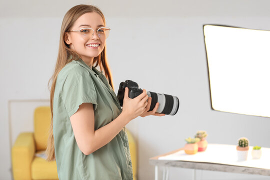 Young female photographer with professional camera in studio