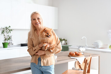 Mature woman with Pomeranian dog in kitchen
