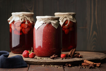 Strawberry jam in glass can with fresh berry and leaf on wood and rustic background, cottagecore...