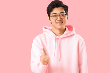 Young Asian man showing thumb-up on pink background