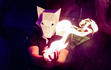 wolf costume with hands of fire. realistic effect of fire between the hands. creative lighting with costume. wolf papercraft. wolf head mask. man in the night with neon light and animal mask. 