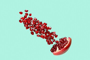 Flying fresh pomegranate with seeds on turquoise background