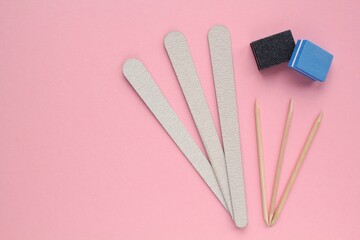 Different abrasive nail polishing files and wooden sticks on pink background. Manicure and pedicure...