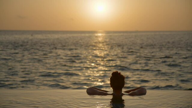 Woman enjoying sunset from luxury ocean villa