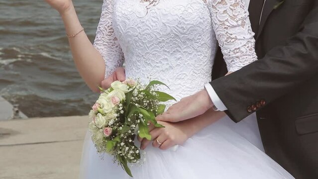 Bride and groom walking on wedding day, girl holding beautiful bouquet of flowers