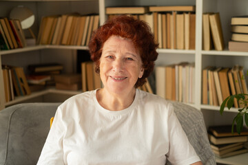 Close-up portrait of a modern elderly woman who sits in a comfortable chair against the background...