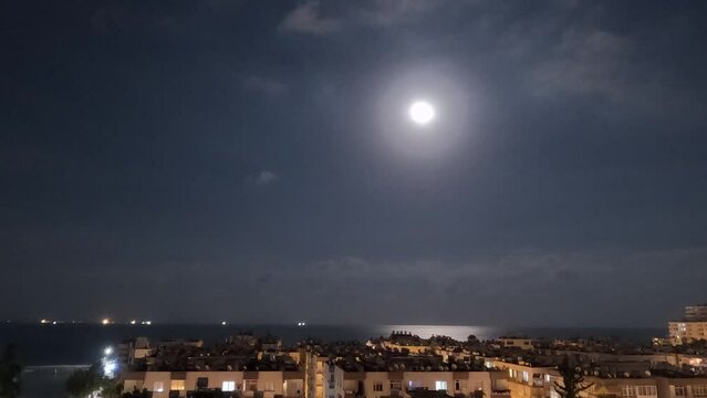 full moonrise over the sea in the clouds over the seaside city. timelapse