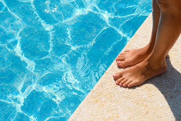 Women's feet by the pool on a summer day. Active recreation concept