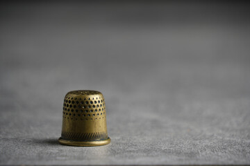 Old brass thimble closeup concrete background.