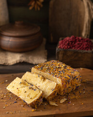 Rustic dark table. Cut pieces of cheese lie on a wooden board
