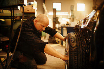 Obraz na płótnie Canvas Experienced male mechanic working in a car mechanics shop