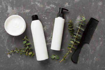 Professional hair care products with comb on concrete background, top view