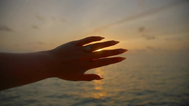 Woman showing engagement ring at sunset